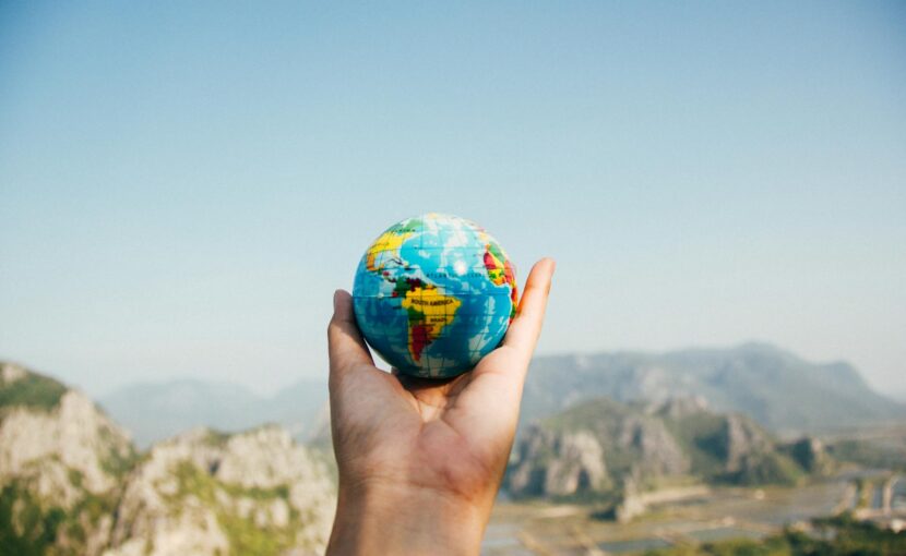 person holding world globe facing mountain