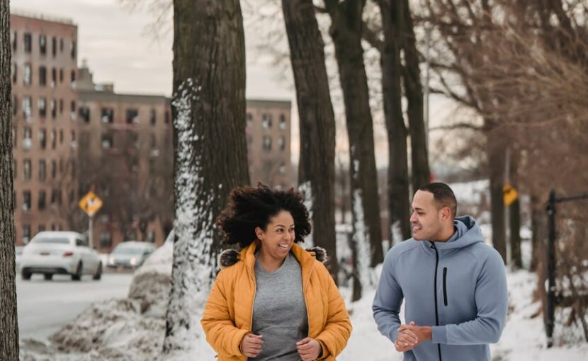 cheerful trainer and black woman running in winter city park