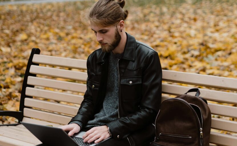 man sitting on a bench using a laptop