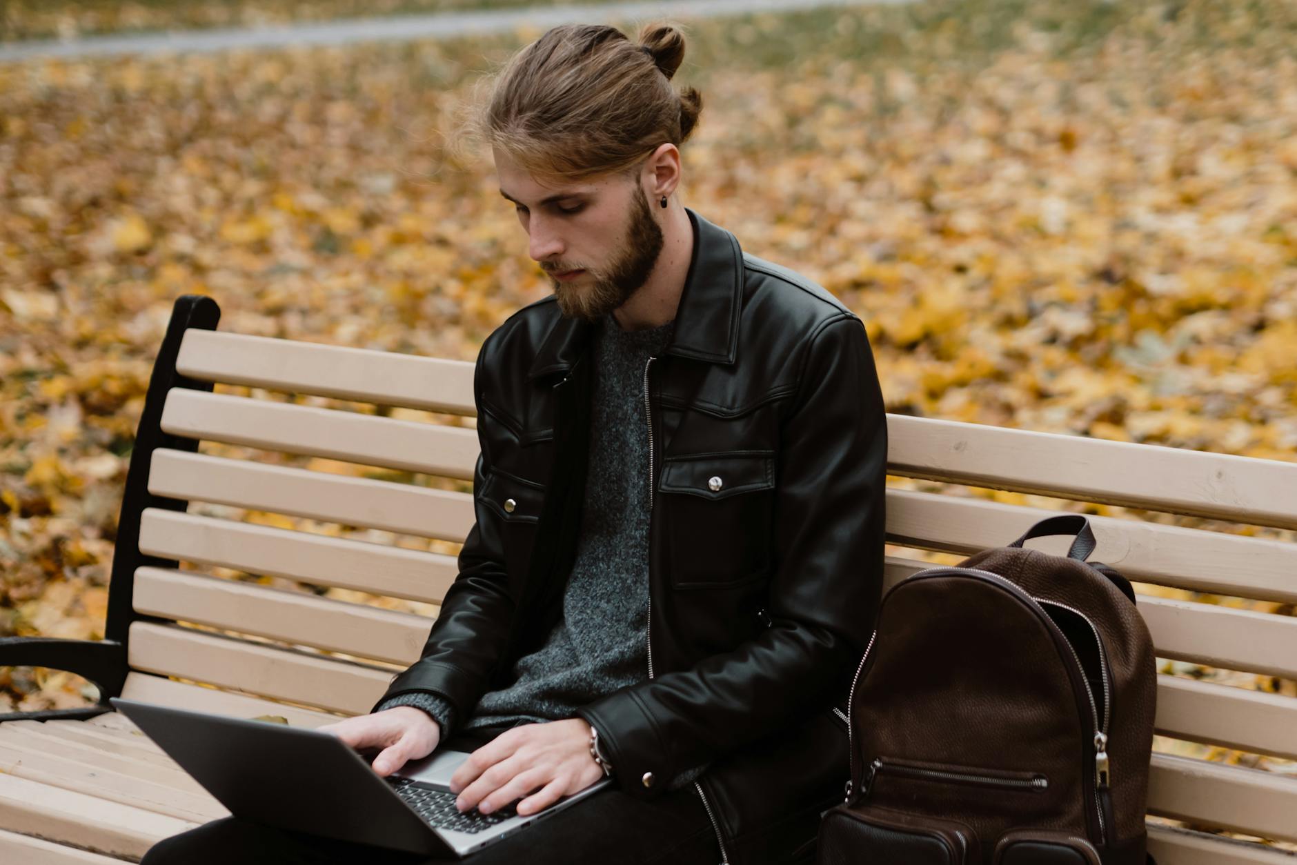 man sitting on a bench using a laptop