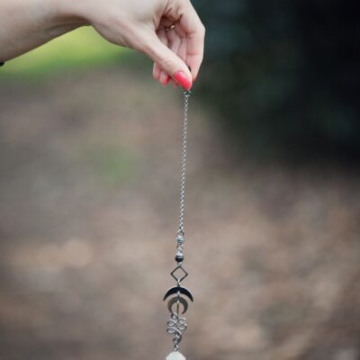 a hand holding a long silver chain with a diamond on it