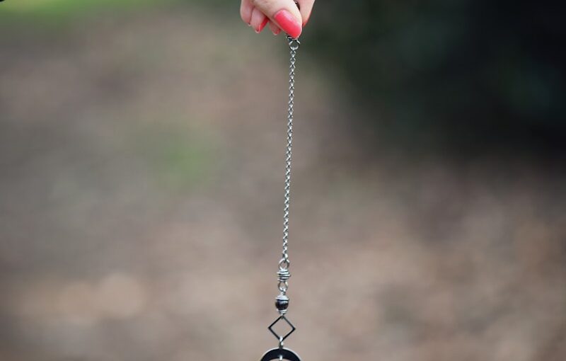 a hand holding a long silver chain with a diamond on it